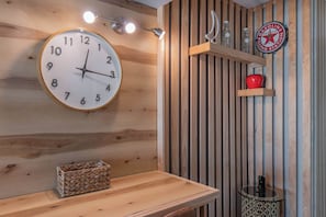 Eine Holzwand mit einer runden Uhr, einem Regal mit Flaschen und einem roten Apfel.