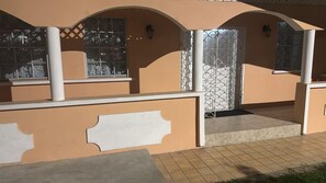 Un edificio con fachada color crema, ventanas de arco y una zona de entrada con azulejos.
