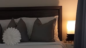 Un lit bien fait, avec une tête de lit, des oreillers et une pancarte au-dessus.