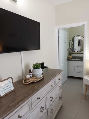 A modern bathroom with a large mirror, a television mounted on the wall, and a wooden vanity with drawers. - OCEANCOMFORT. (Lucea)