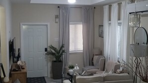 Un salon avec un canapé, une table basse, une plante en pot, une lampe et un miroir.