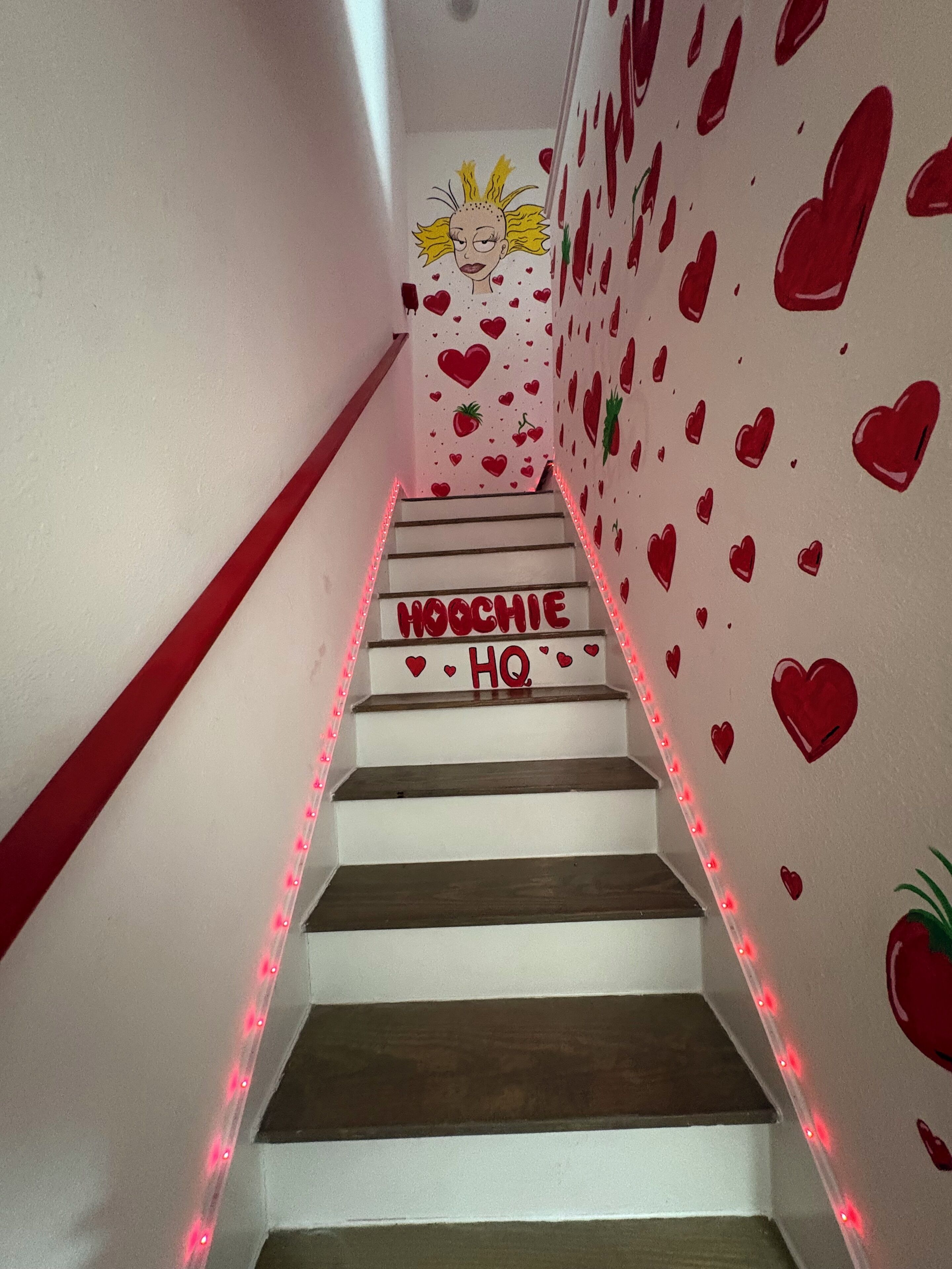En trappa med röda LED-lampor, en vägg med hjärtmönster och texten ”HOCHIE HQ”.