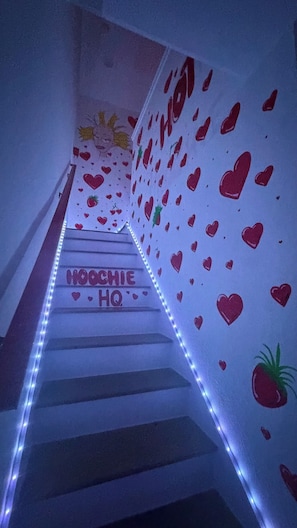 Un escalier orné de motifs en forme de cœur, avec l’inscription « HOOCHEE HQ » sur les marches.