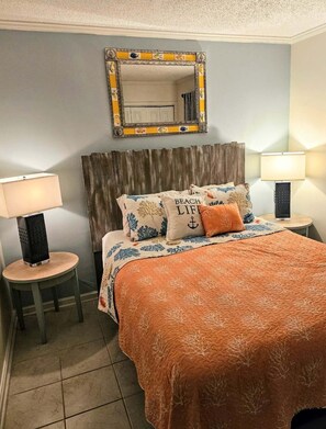 Ein Schlafzimmer mit einem Bett, zwei Nachttischen, einem Spiegel und einem Kopfteil.