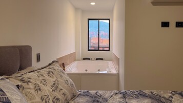 Un dormitorio con cama, ventana con vistas y bañera.