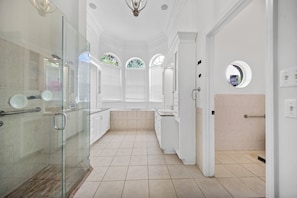 A spacious bathroom with a glass shower enclosure, a bathtub, and a vanity with a mirror.