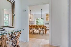 Een moderne keuken met een eettafel met glazen blad, houten stoelen en hanglampen.
