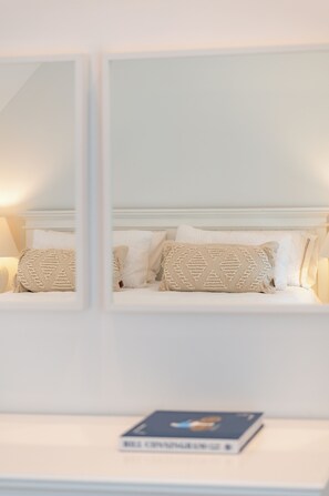 Een keurig opgemaakt slaapkamer met een bed, kussens en een boek op een nachtkastje.
