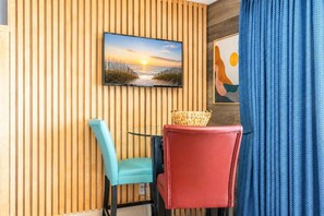 Ein Zimmer mit einer Wand aus Holzlatten, einem Fernseher über einem Tisch mit zwei Stühlen und einem blauen Vorhang.