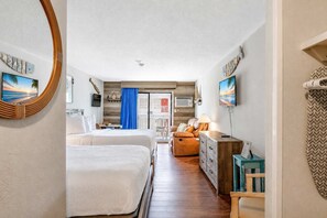 Ein Hotelzimmer mit zwei Betten, einem Schlafsofa, einem Fernseher und Meerblick.