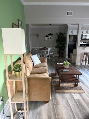 En stue med sofa, sofabord og spiseområde med stole og bord.