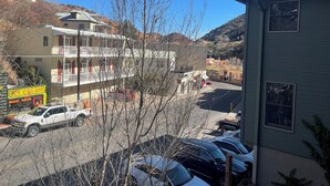 Un immeuble à plusieurs étages doté de balcons, d’un parking et surplombant un paysage montagneux.