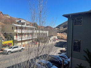 Un edificio a più piani con balconi, un parcheggio e uno sfondo montuoso.