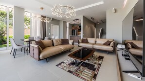 A modern living room with a sofa set, a coffee table, and a chandelier. - Luxe Green Coast Villa Jacuzzi Free Buggy (Himarë)