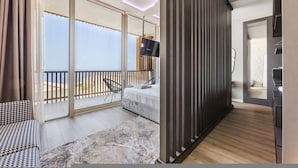 A modern hotel room with a balcony, a bed, a TV, and a wooden floor. - Luxe Green Coast Villa Jacuzzi Free Buggy (Himarë)