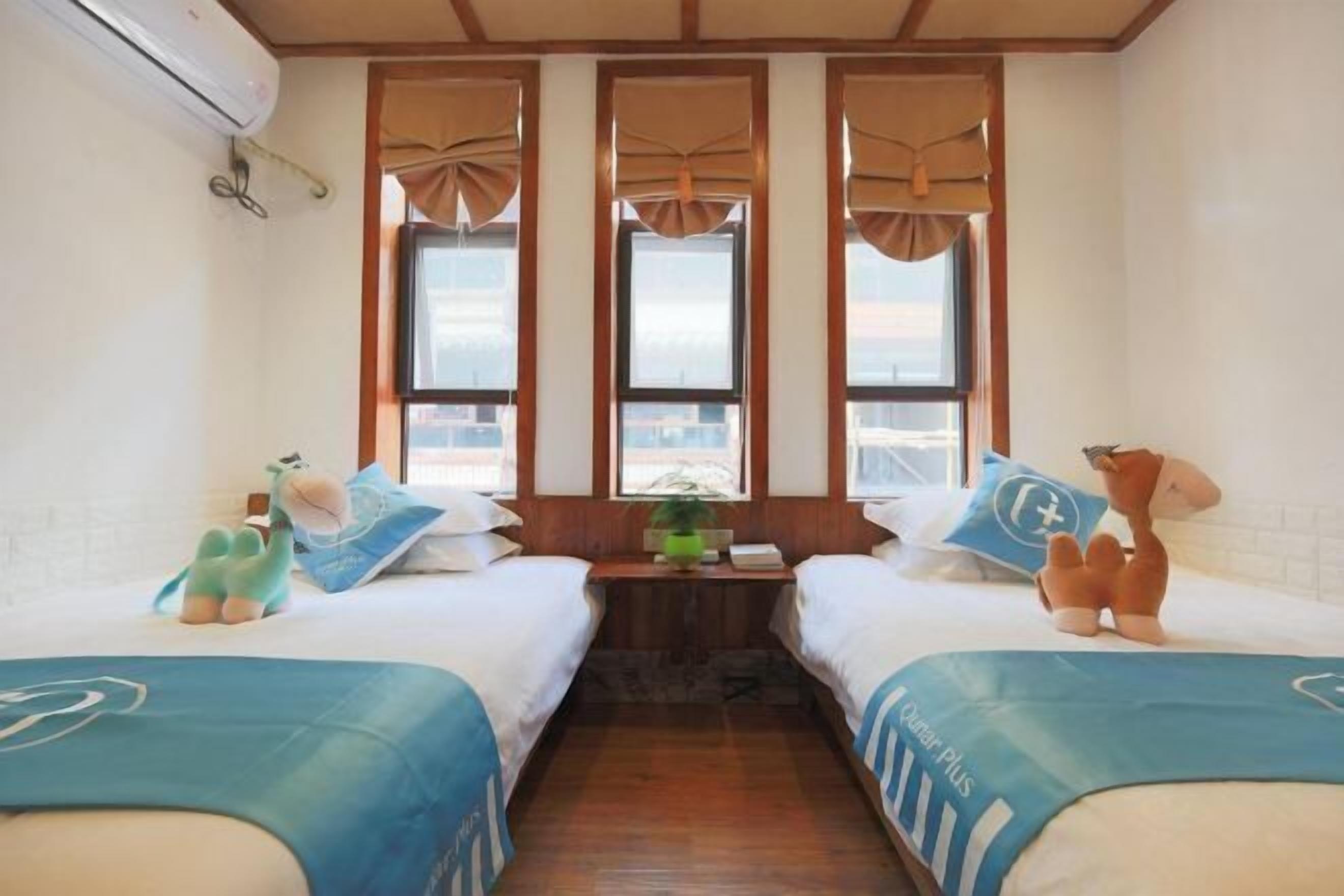 Quarto de hotel com duas camas, uma mesa pequena e vista pela janela.