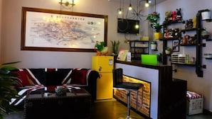 A hotel lobby with a sofa, a coffee table, a reception desk, a map on the wall, and shelves with plants and decorations. - Jiuqi Zhangjiajie Yunqin Boutique Inn (National Forest Park Wulingyuan Biaozhimen) (Zhangjiajie)