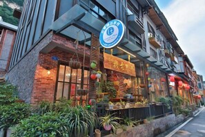 A building with a sign indicating a restaurant, outdoor seating with plants, and a clear sky. - Jiuqi Zhangjiajie Yunqin Boutique Inn (National Forest Park Wulingyuan Biaozhimen) (Zhangjiajie)