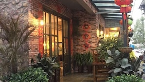 A brick building with a glass door entrance, potted plants, and hanging lanterns. - Jiuqi Zhangjiajie Yunqin Boutique Inn (National Forest Park Wulingyuan Biaozhimen) (Zhangjiajie)