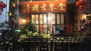 A restaurant with a brick facade, large windows, and outdoor seating with potted plants. - Jiuqi Zhangjiajie Yunqin Boutique Inn (National Forest Park Wulingyuan Biaozhimen) (Zhangjiajie)