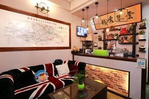 A hotel lobby with a sofa, a coffee table, a television, and a brick wall. - Jiuqi Zhangjiajie Yunqin Boutique Inn (National Forest Park Wulingyuan Biaozhimen) (Zhangjiajie)