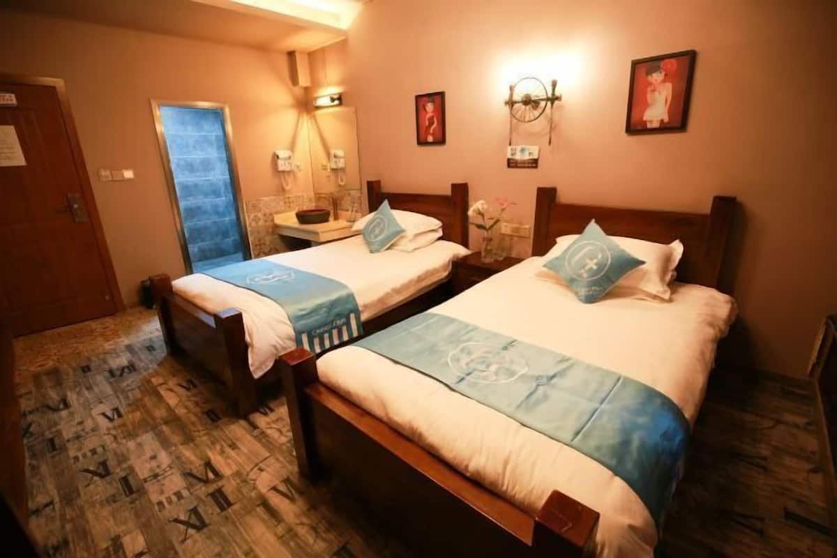 A hotel room with two beds, a bathroom, and a view of the sea.