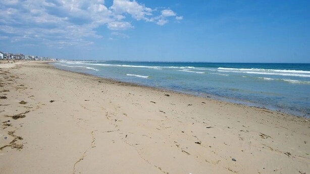 Ein Strand mit blauem Himmel und Meereswellen.