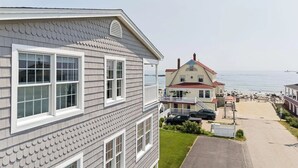 Ein Küstenhaus mit Balkon, Meerblick und einem gepflasterten Weg.