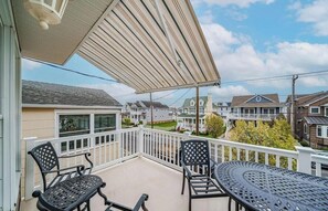 Un balcon avec une balustrade blanche, deux chaises et une table.