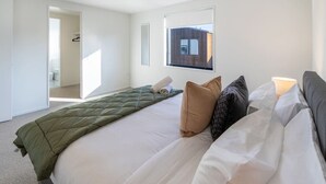 A hotel room with a large bed, a window, and a door leading to a bathroom. - Family Friendly Home near Fitzgerald Ave + Garage (Christchurch)