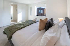 Ein Hotelzimmer mit einem großen Bett, einem Fenster und einer Tür zu einem Badezimmer.