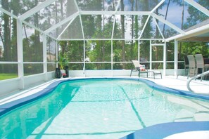 Ein Schwimmbecken mit Glasumrandung, umgeben von Stühlen und einem überdachten Bereich.