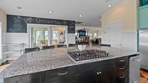 A kitchen with a granite countertop, stainless steel appliances, and a chalkboard wall with writing. - "Escape" 5 Bedrooms, 6.5 Bathrooms, ICW Home, Community Pool and Tennis Court! (Supply)