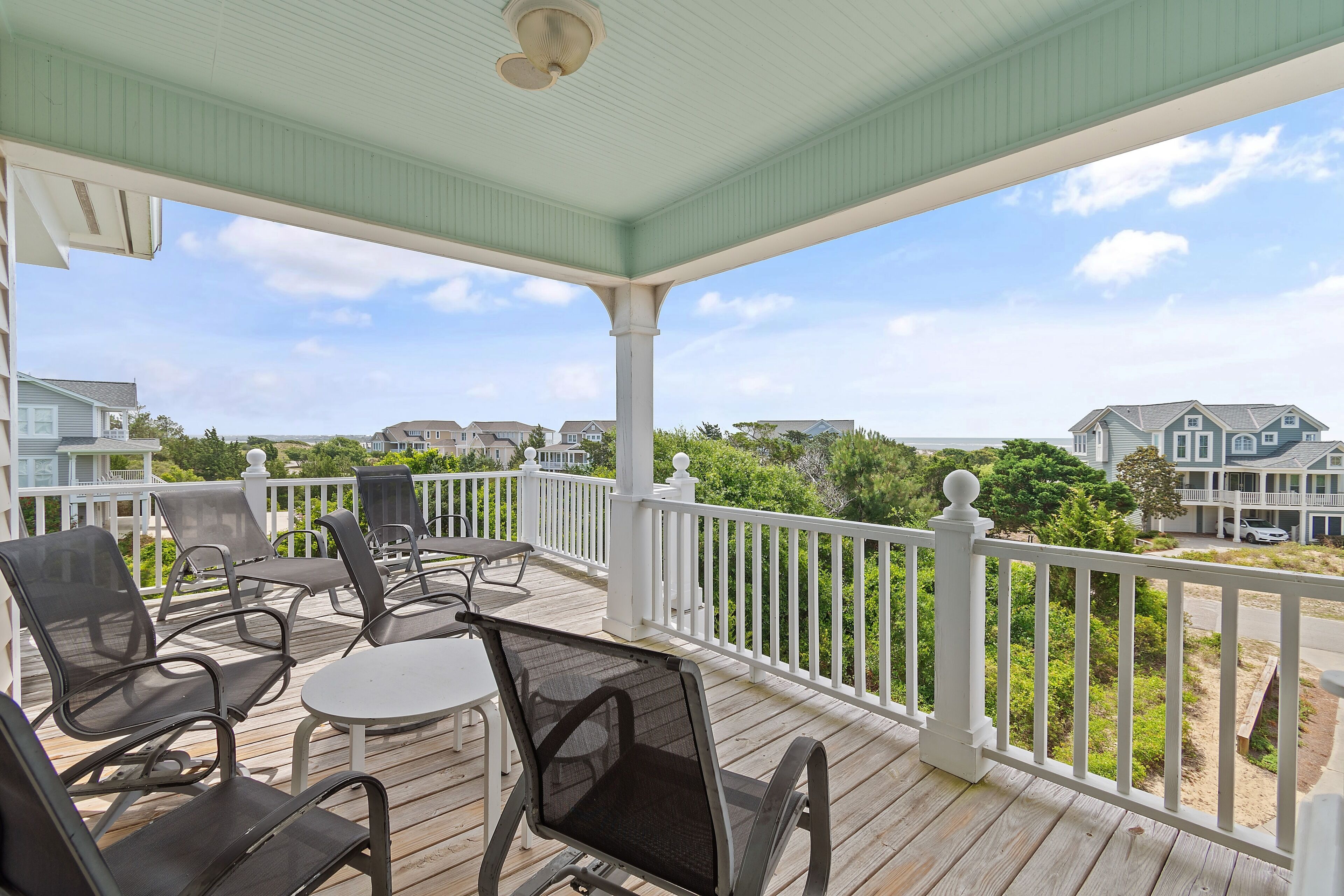 A covered outdoor deck with seating and a view of the surrounding neighborhood.