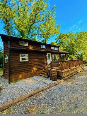 A wooden cabin with a porch, steps, and a gravel driveway. - 3 Tiny Cabins Together (Indianapolis)