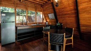 Interior em madeira com cozinha, sala de jantar e janela com vista para o verde.