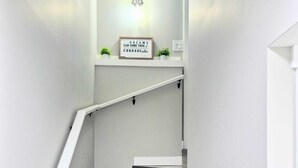 A staircase with wooden steps and a white handrail, leading to a landing with a motivational sign and small plants. - Femkem Cozy Suite in a peaceful and beautiful neighborhood. You will love it. (Regina)