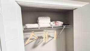 A closet with shelves, hangers, and folded towels. - Femkem Cozy Suite in a peaceful and beautiful neighborhood. You will love it. (Regina)