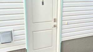 A white door with a 'B' marking, a mailbox, and a wall-mounted light fixture. - Femkem Cozy Suite in a peaceful and beautiful neighborhood. You will love it. (Regina)