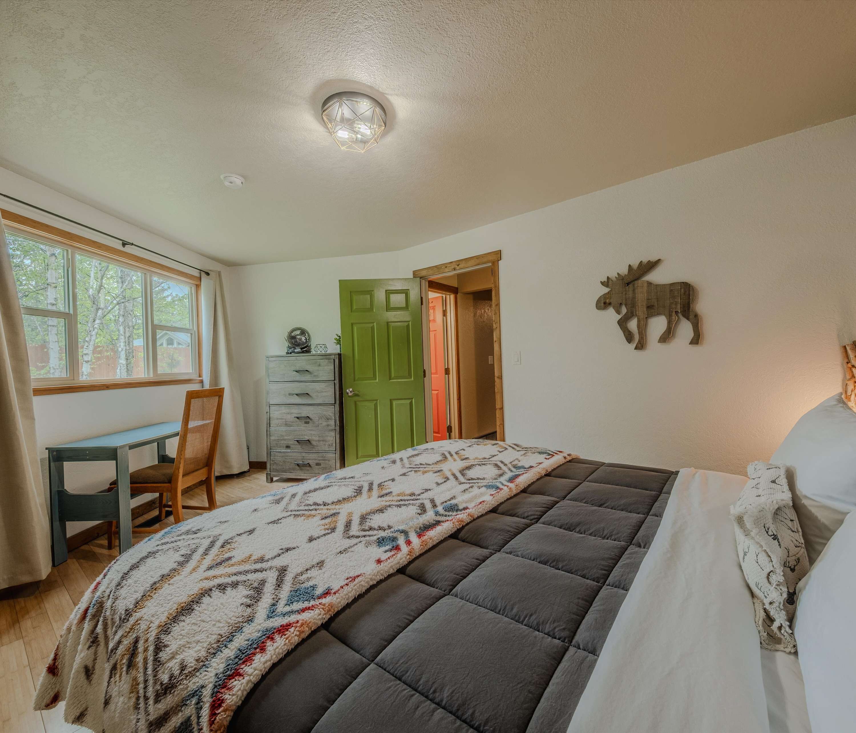 Ein Schlafzimmer mit einem Bett, einem Schminktisch, einem Stuhl, einem Fenster und einer Tür.
