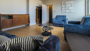 Una sala de estar moderna con un sofá, sillones, una mesa de centro y un aparador de madera.