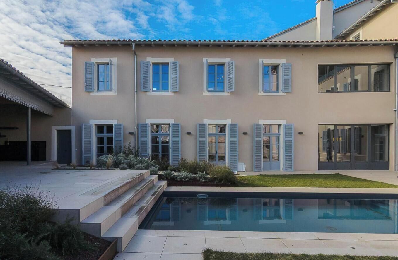 A two-story building with a swimming pool, large windows, and a flat roof.