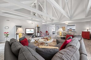 A spacious living area with a high ceiling, a sofa set, a dining table, and a kitchen in the background. - 2BR villa with Community Pool, Private Patio, Spacious Kitchen, & Open-Concept Living Spaces (Hilton Head Island)