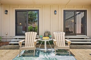 A patio with two Adirondack chairs, a round table, and a small yellow bowl. - 2BR villa with Community Pool, Private Patio, Spacious Kitchen, & Open-Concept Living Spaces (Hilton Head Island)