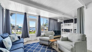 Ein Zimmer mit blauem Teppichmuster, einer Couch, einem Sessel, einem kleinen Tisch und einem Etagenbett.