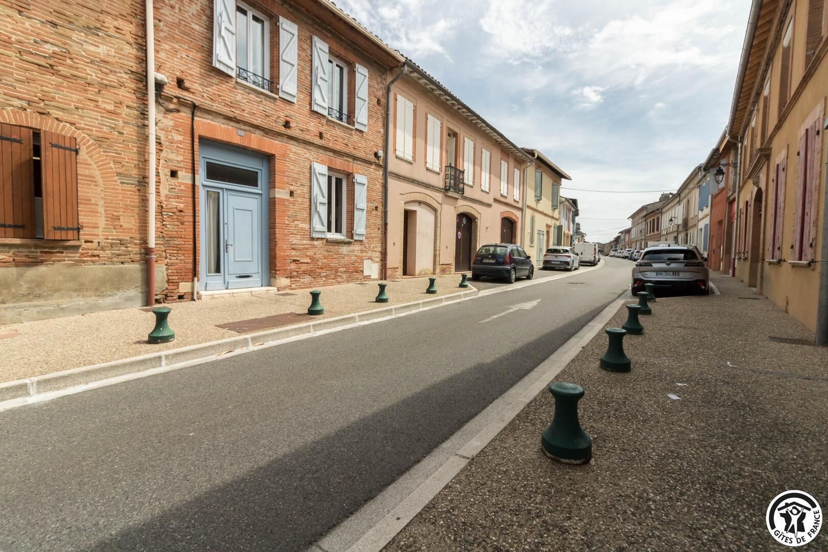 A street with buildings, a blue door, and parked cars.