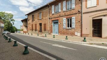 A street with a row of traditional brick buildings, a blue door, and green bollards lining the road.