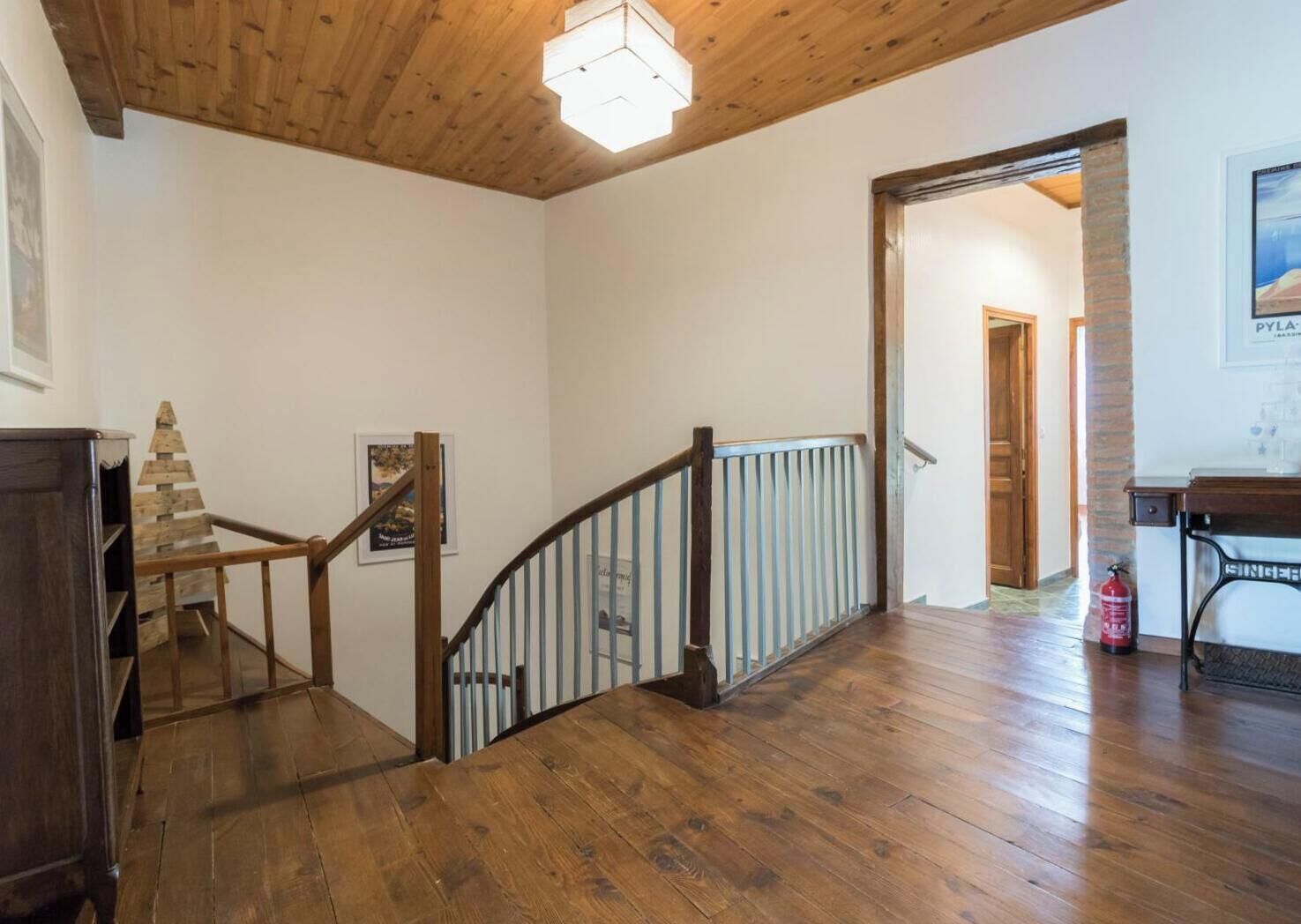 A wooden staircase with a railing, a wooden floor, and a ceiling light fixture.