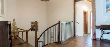 A wooden staircase with a railing, a wooden floor, and a ceiling light fixture.