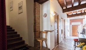 A staircase leading to a room with a brick wall, a wooden chair, a door with a light switch, and a wooden ceiling. - La Casa de Mamita - FRONTON (FRONTON)